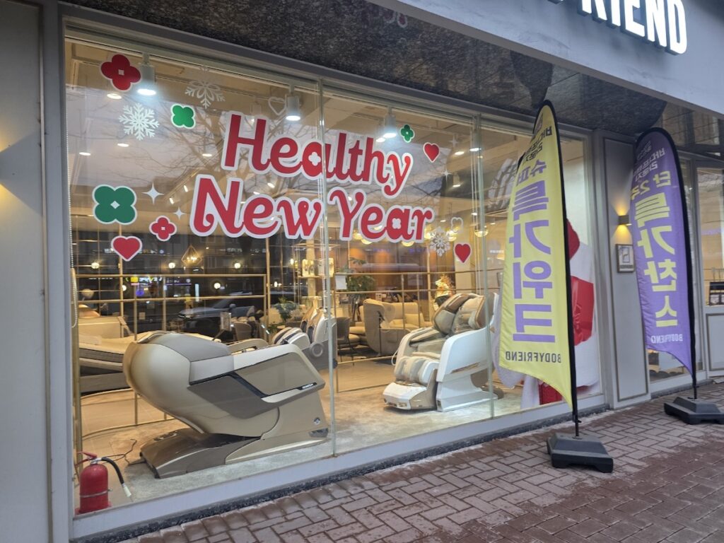 Luxury **Korean Massage Chairs** showcased in a high-end storefront for New Year wellness.