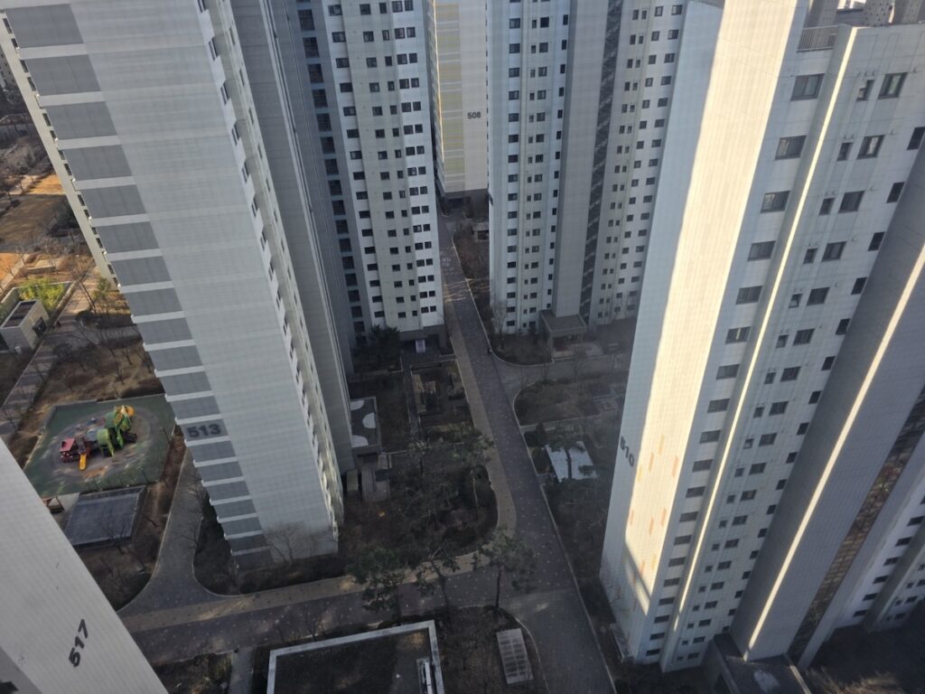 A bird's-eye view of a modern Korean apartment complex, showing the organized layout and children's playground, ideal for those signing a Korean Real Estate Contract.