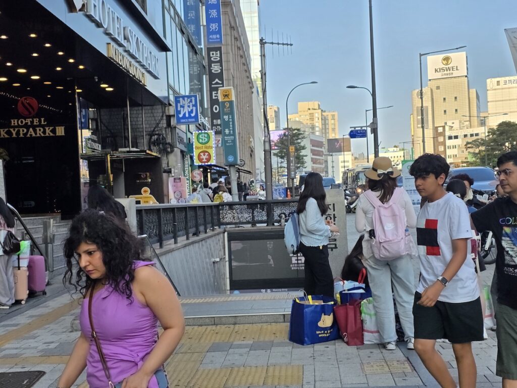 most-crowded-places-seoul-weekends-myeongdong-station-exit-tourists Foreign tourists with shopping bags at Myeongdong Station exit showing most crowded places in Seoul on weekends near Hotel Skypark