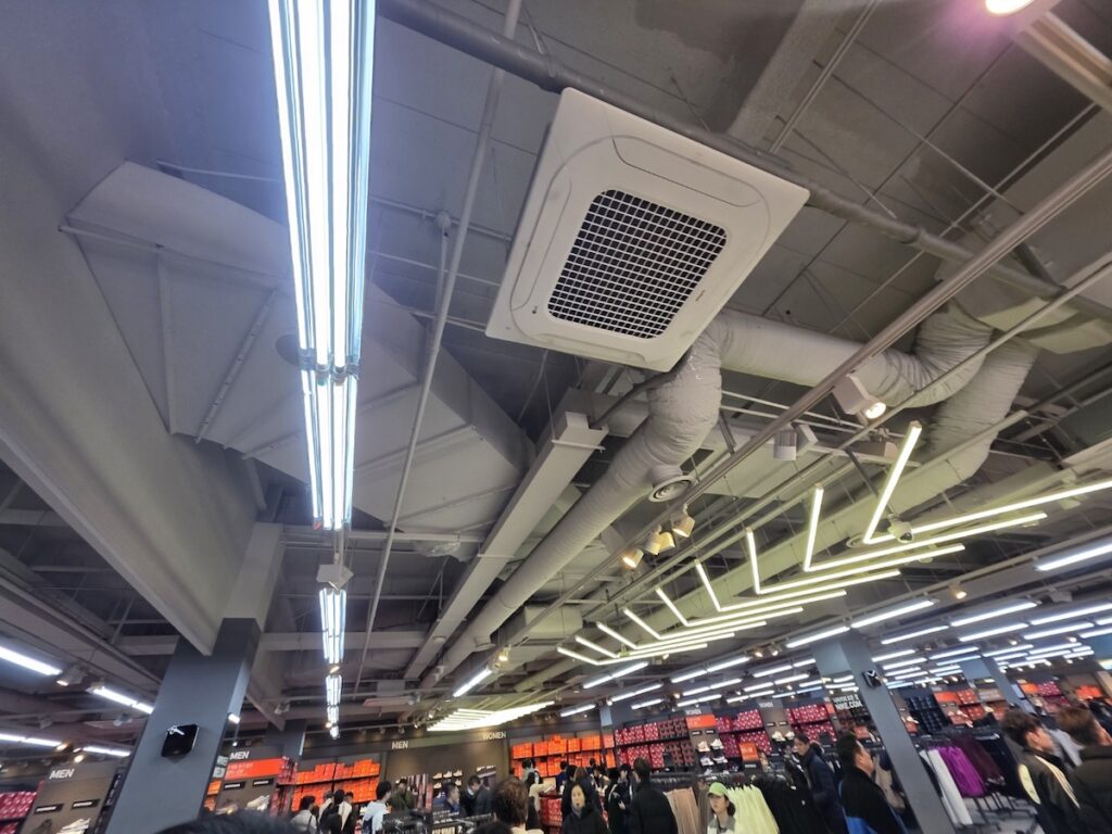 nike-factory-store-paju-interior-crowd The high-velocity atmosphere inside the Nike Factory Store at Shinsegae Simon Premium Outlets Paju, featuring vast inventory and busy shoppers.
