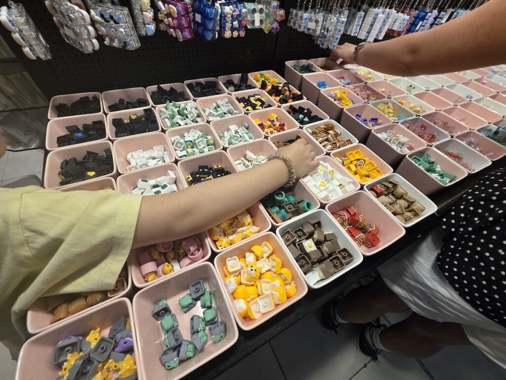 A vibrant street vendor stall in Seoul filled with countless colorful mechanical switches and character keycaps for a custom Korean keycap keyring project.
