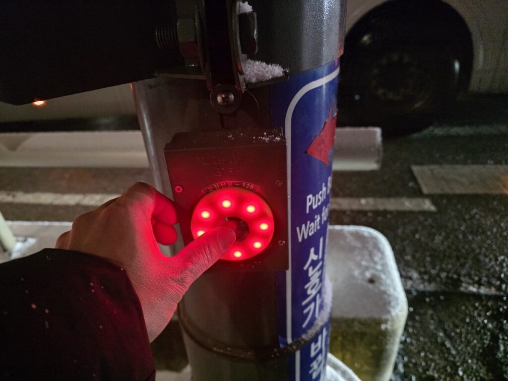 pedestrian-push-button-seoul-traffic-signal A yellow pedestrian push-button for traffic signals in Seoul, an essential safety feature for winter walking.