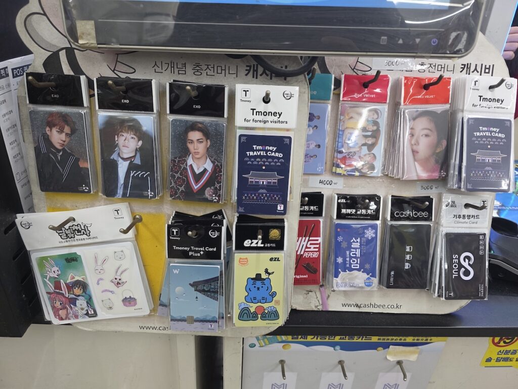 A retail display rack inside a Seoul convenience store filled with various Korean transit passes like Tmoney, EZL, and the Seoul Climate Card, offering an alternative spot to recharge Climate Card with foreign credit card options safely.