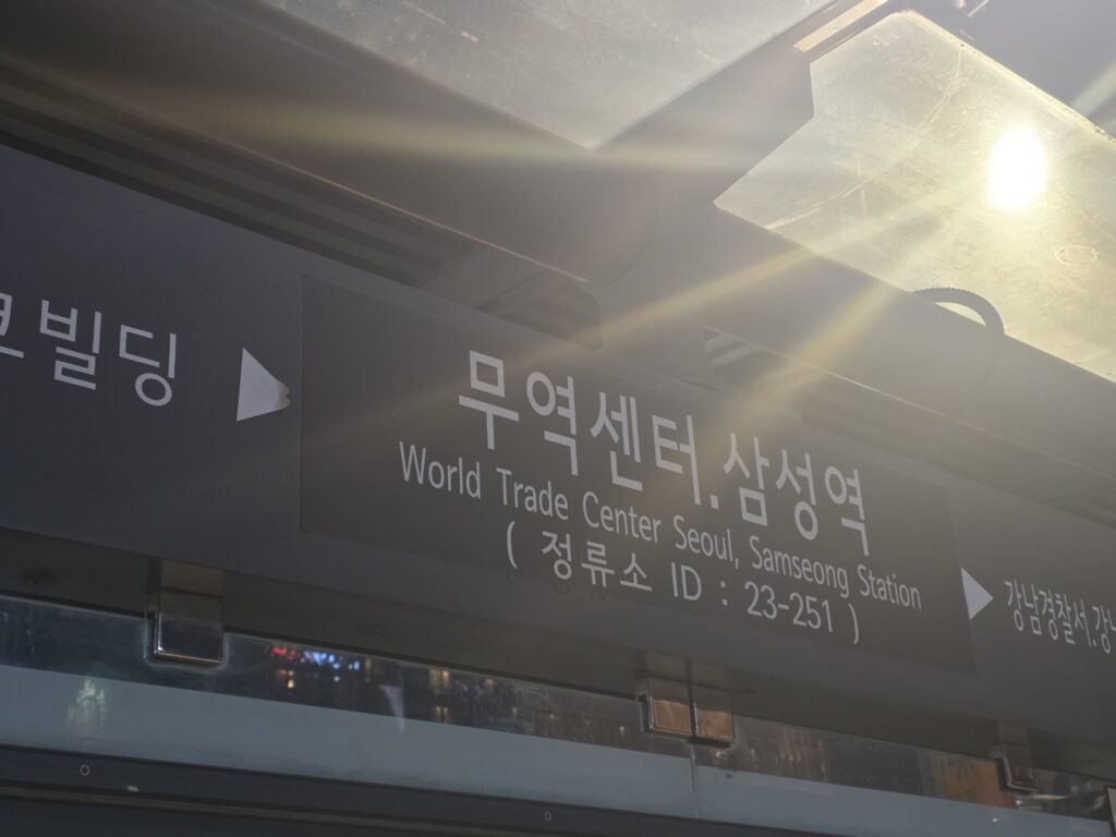 A bus stop near Samseong Station in Gangnam, showing passengers, city lights, and the urban transportation environment around COEX.