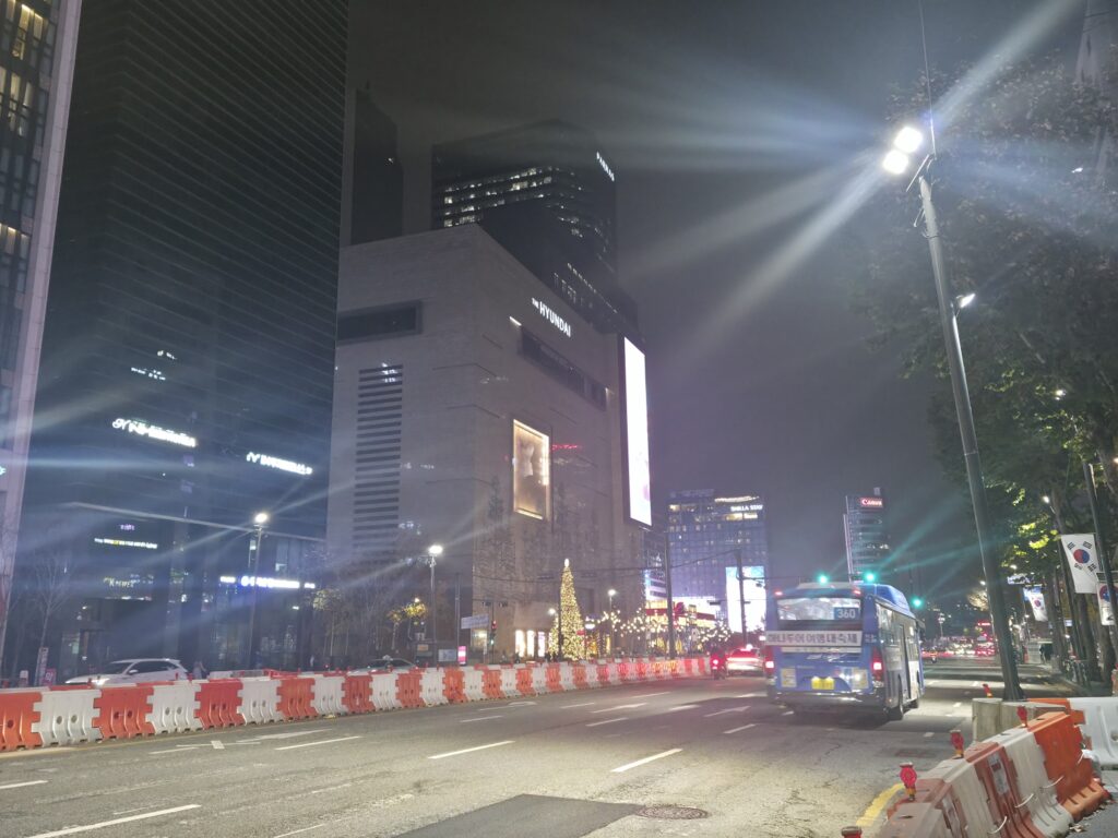 A street view near Samseong Station in Gangnam, featuring modern buildings and busy pedestrian sidewalks.