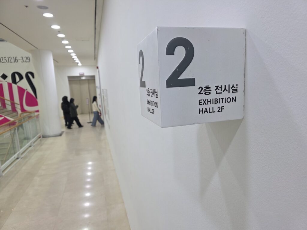 sema-exhibition-hall-2-signage-seoul A white cube-shaped directional sign for "Exhibition Hall 2F" inside the Seoul Museum of Art (SeMA), the venue for Free Art Exhibition Seoul 2026.