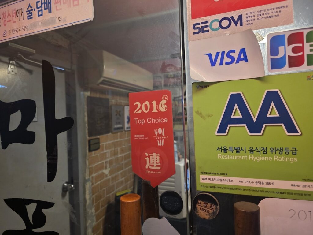 seoul-best-restaurants-safety-certified-sticker Close-up of the Seoul Safety Restaurant certification on a glass door of one of the Seoul Best Restaurants.