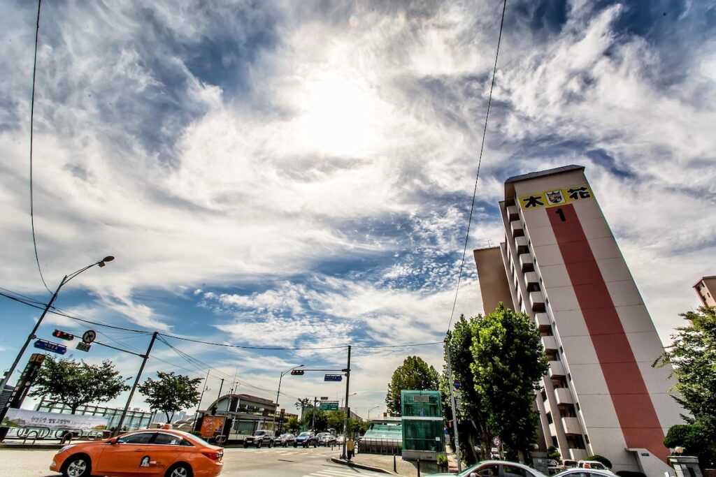 seoul-city-taxi-transit-ritual Korea Travel: Budget Saving Guide - An orange taxi navigating a Seoul intersection under a dynamic sky.