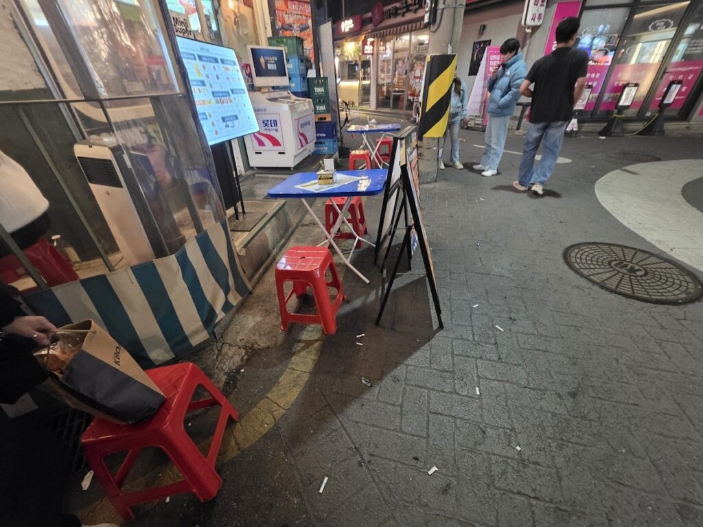 seoul-east-guide-2026-yellow-plastic-chair-ritual A classic yellow plastic chair on a Seoul street, symbolizing the local street food ritual of Seoul East Guide 2026.