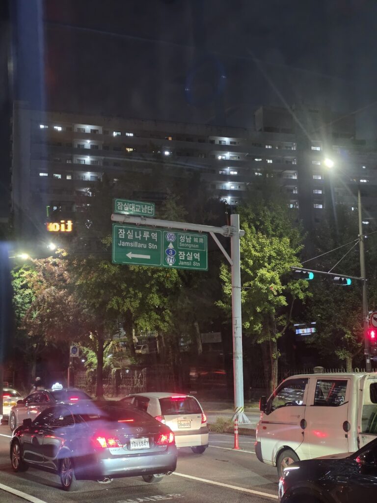 “Seoul Jamsil night street with people walking and illuminated city lights”