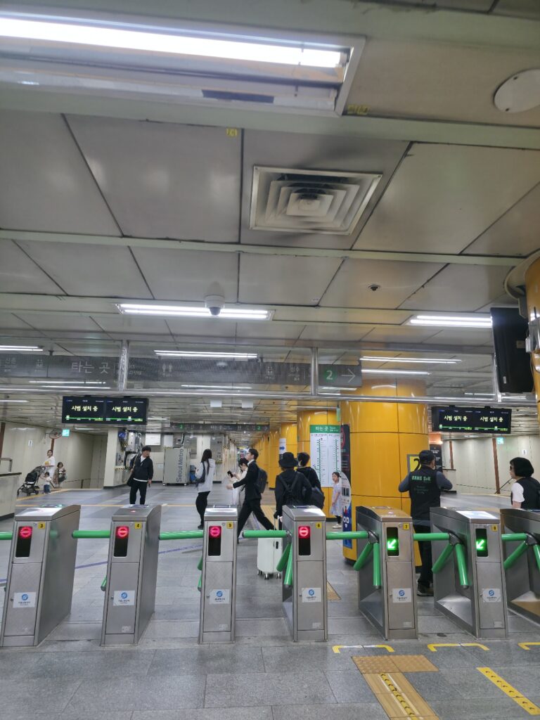 Ticket gates at a Seoul Subway Line 2 station, with turnstiles and T-money card readers.