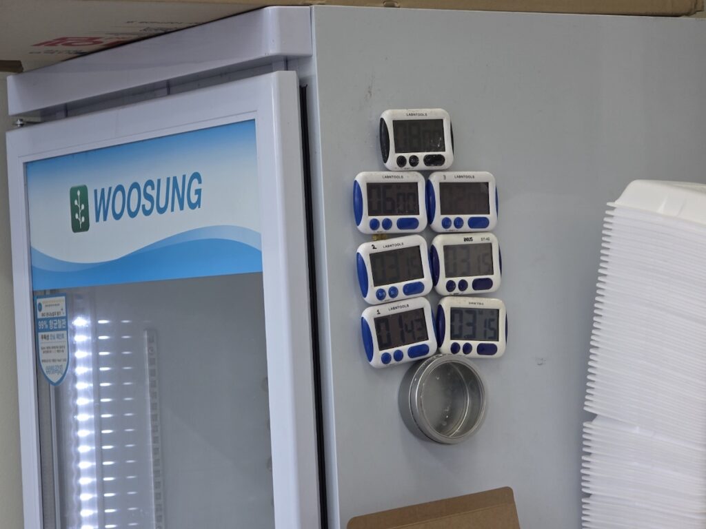 seoul-mandu-protocol-precision-timers Seven digital timers on a refrigerator used to master the Seoul mandu protocol of precise steaming.