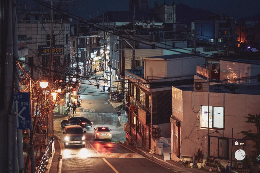 seoul-night-alley-street-lights A quiet night alley in Seoul illuminated by warm street lights, showing local shops and urban atmosphere.