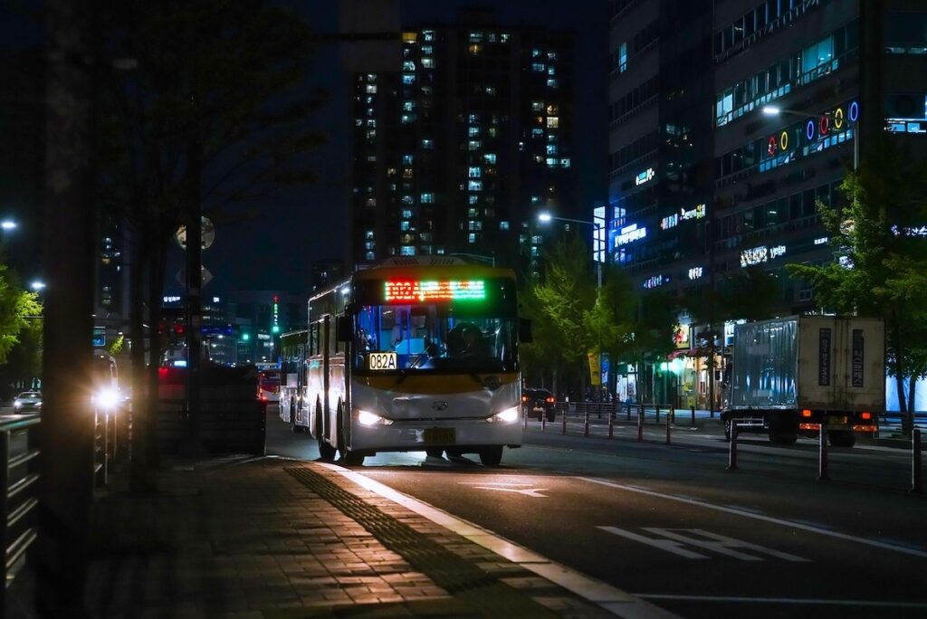 seoul-night-bus-t-money-payment-system A cinematic night view of a Seoul city bus arriving at a stop, where passengers use T-money for contactless transit payments.