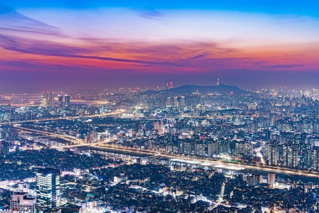 A breathtaking nighttime panoramic view of the Seoul skyline and N Seoul Tower, showcasing the 24-hour urban vibrancy for those wondering **why Seoul is the best winter escape for Londoners in 2026**.