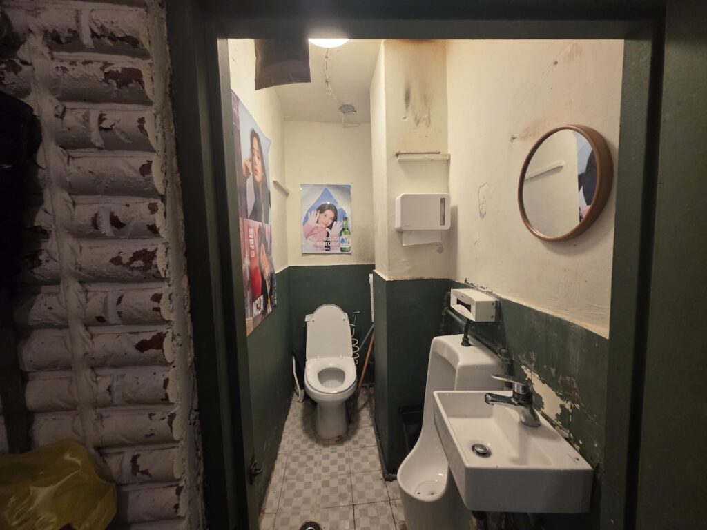Close-up of a Seventeen poster inside a Konkuk University pub restroom, part of the visual Seoul Restroom Rituals 2026.
