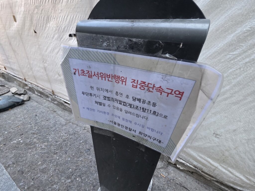 seoul-smoking-laws-wall-warning-sticker A red and white no-smoking sticker on a brick wall, serving as a visual guide for the Seoul Smoking Laws to prevent tourists from illegal smoking in alleys.