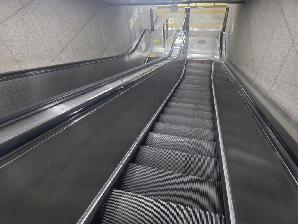seoul-subway-long-escalator-gwanghwamun-station A long, wide-angle view of the deep **Korea Subway Escalator** system at Gwanghwamun Station, showing the immense scale of Seoul’s underground transportation network.