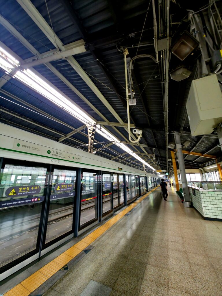 Platform screen doors in a Seoul subway station with safety markings and door indicators