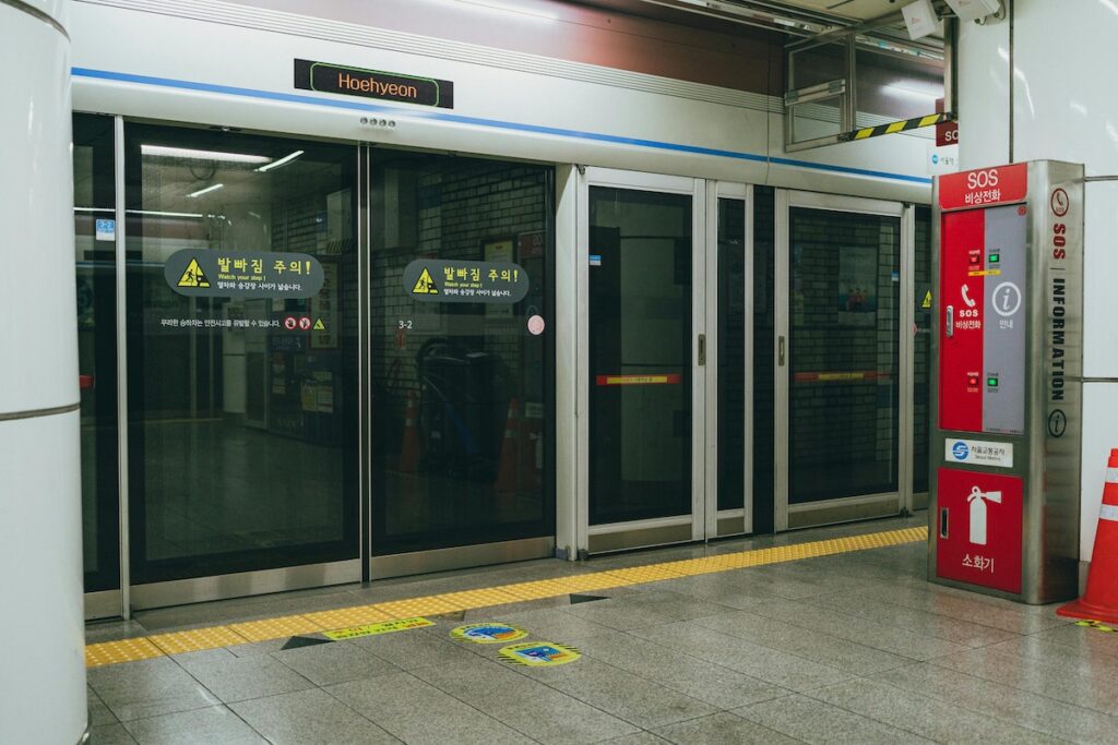 seoul-subway-screen-doors “Seoul subway station platform with glass screen doors for passenger safety and train boarding”