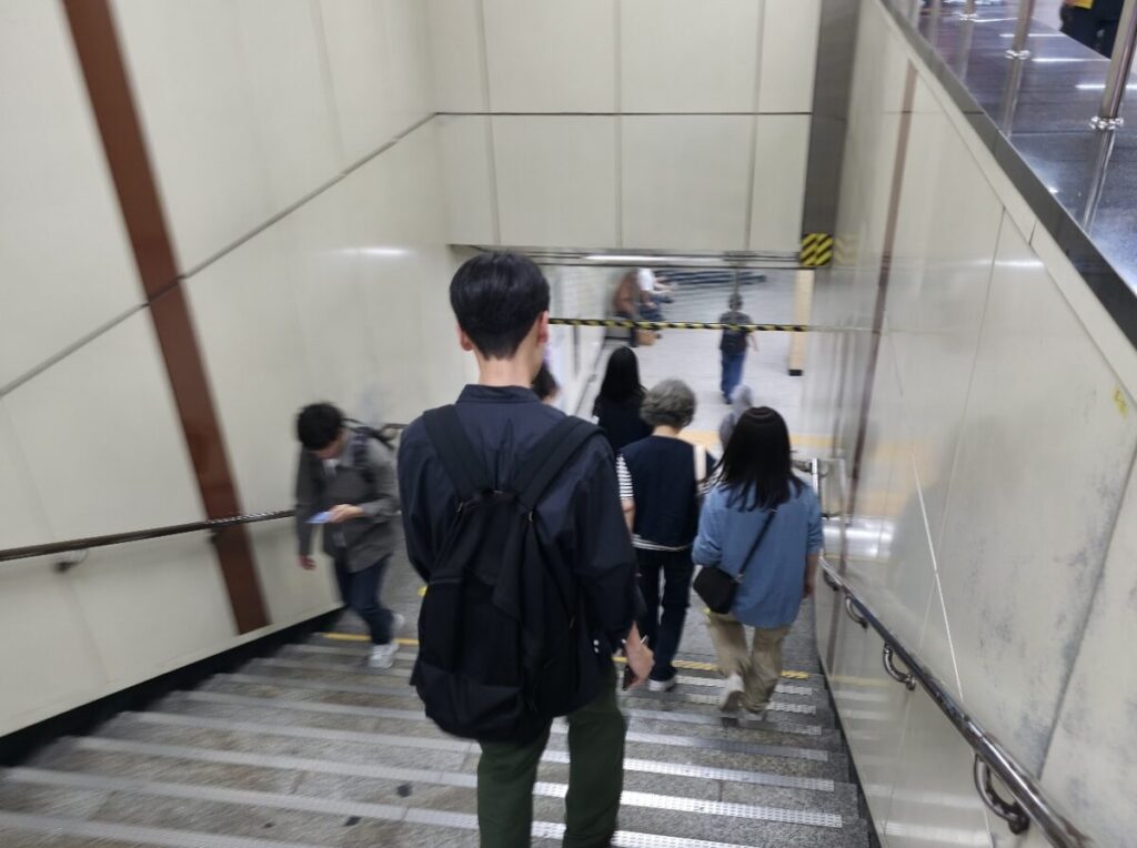 People navigating steep subway stairs, illustrating why you need the Best Walking Shoes for Korea.