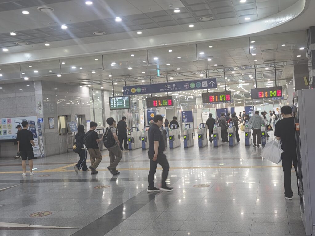 seoul-summer-travel-subway-station Commuters walking through turnstiles at a fully air-conditioned subway station during Seoul summer travel.