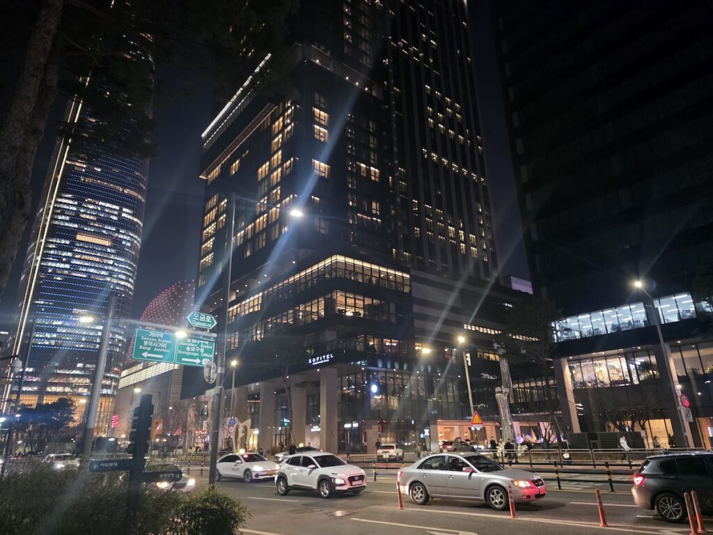 seoul-travel-mistakes-jamsil-night-commercial-district Seoul travel mistakes image showing Jamsil at night with tall buildings, traffic, hotels, and bright city lights