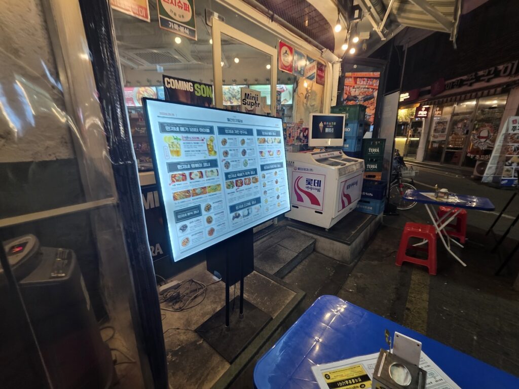 seoul-travel-mistakes-local-restaurant-night Seoul travel mistakes image showing a local Korean restaurant entrance at night with menus, outdoor tables, and neighborhood streets