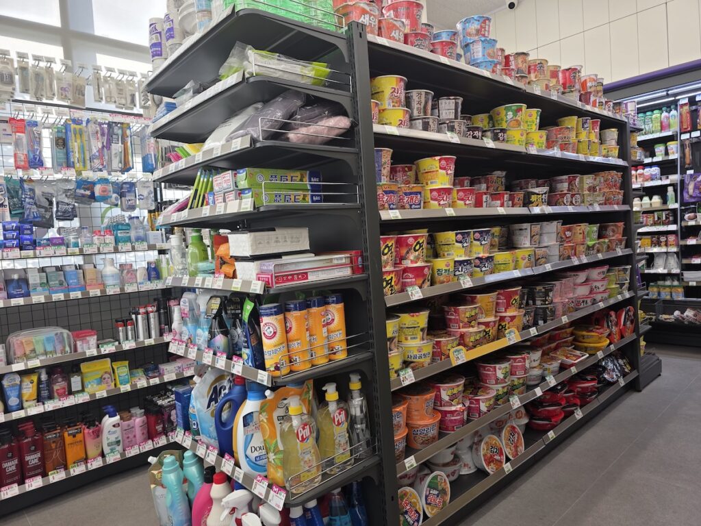 Shelves stacked with dozens of varieties of cup ramen and instant noodles inside a South Korea convenience store.