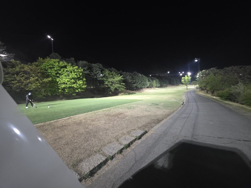 south-korea-golf-prices-night-golf-session A golfer teeing off under bright stadium lights during a night golf session on a South Korean course.