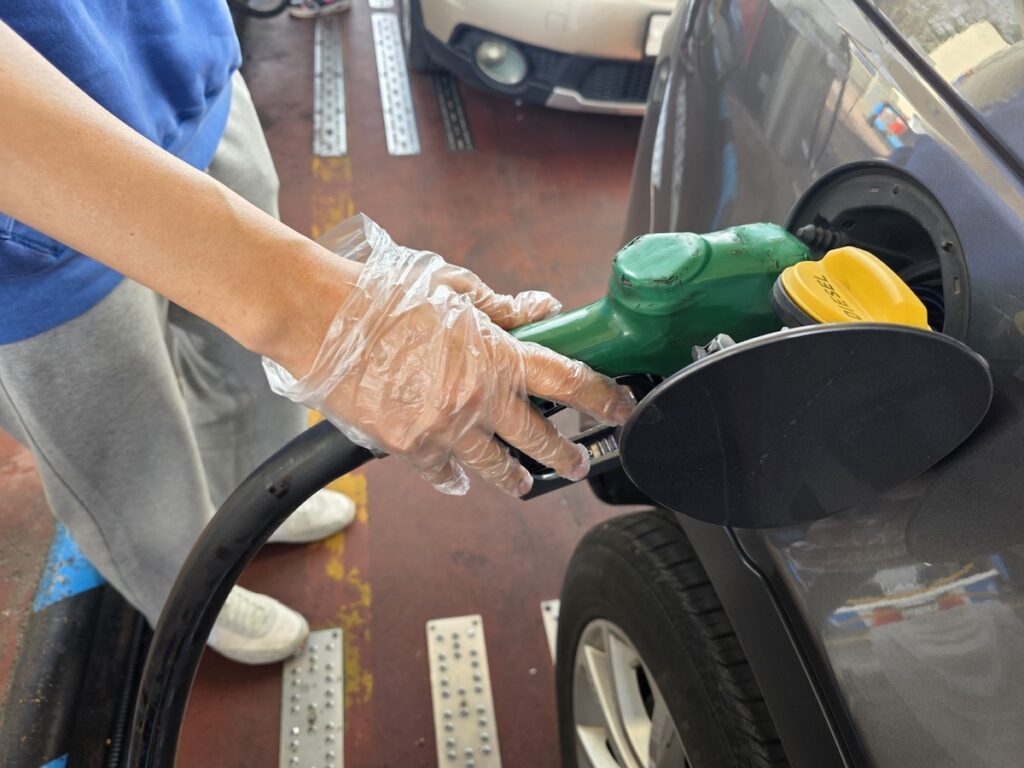 south-korea-highway-gas-station-prices-2026-vinyl-glove A driver using a disposable vinyl glove to handle the nozzle, a unique ritual for South Korea Highway Gas Station Prices 2026.