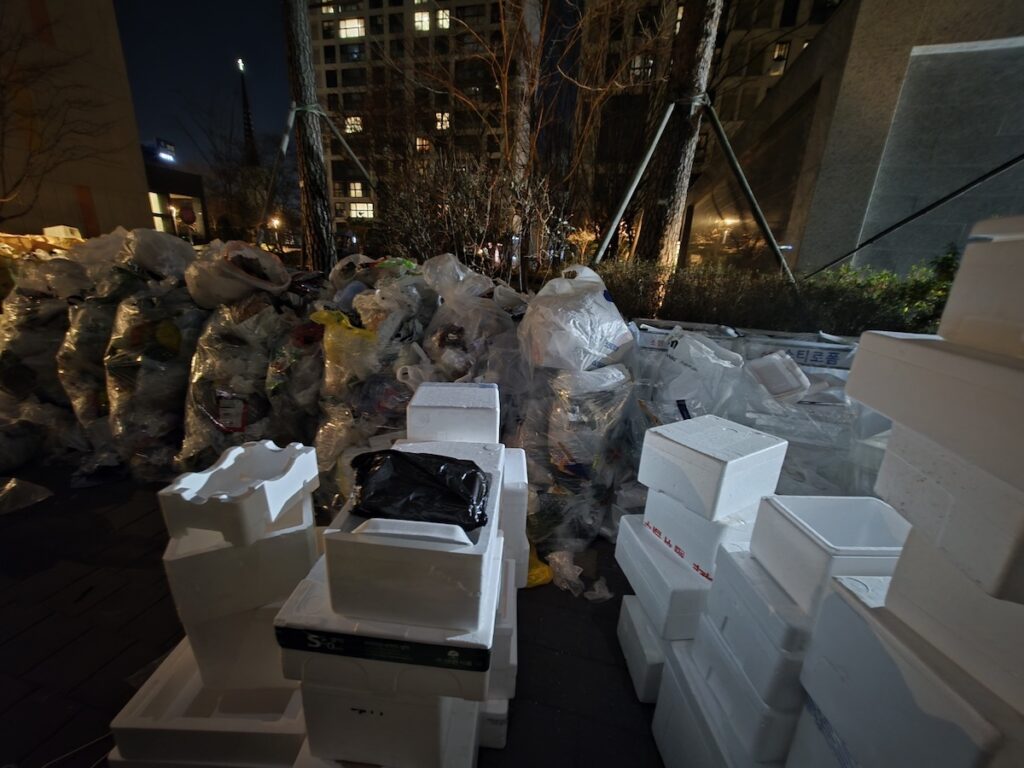 Large stacks of white styrofoam boxes from food and parcel deliveries at an apartment recycling station in South Korea.
