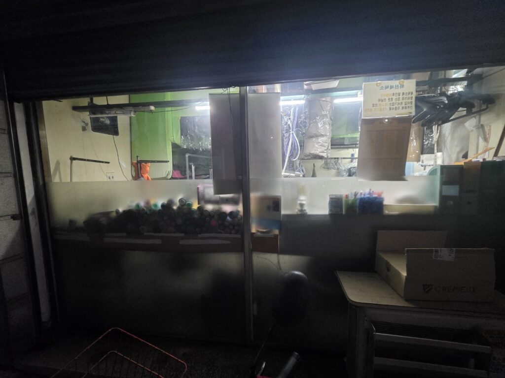 Inside a **Korean Laundrette** showing alteration threads. Close-up of a Korean laundry master's desk featuring colorful thread spools and sewing equipment used for professional garment alterations.