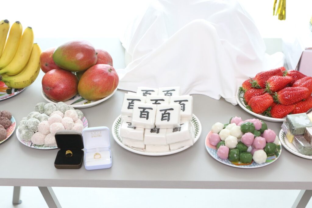 A beautifully arranged traditional Dol-sang table for a Korean first birthday, featuring various rice cakes, fruits, and gold rings.
