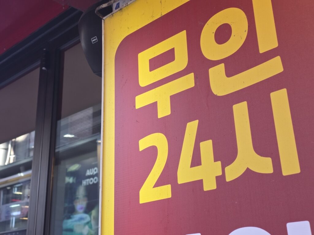 travel-korea-on-a-budget-24h-unmanned-retail A sign for an unmanned shop in Seoul, showcasing a high-tech way to travel Korea on a budget with 24-hour convenience.