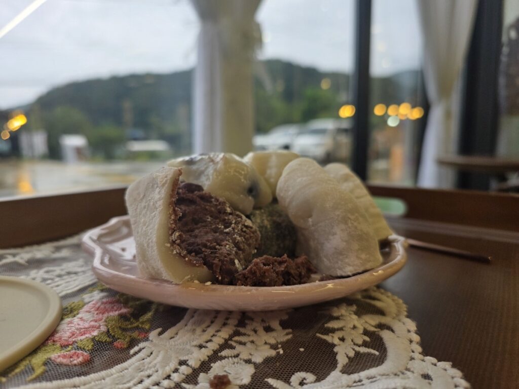 tteok-cafe-view-yongmunsan-mountain A plate of assorted Korean rice cakes with a scenic view of Yongmunsan Mountain in the background, from the Korean tteok rice cake guide 2026.