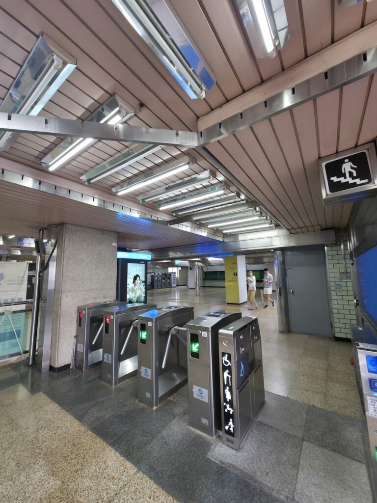 wheelchair-accessible-seoul-subway-elevator-priority A bright, silver-colored elevator inside a modern Seoul subway station with a clear wheelchair and elderly priority sign. The elevator is located at a spacious platform, showing a clean and high-tech barrier-free infrastructure in South Korea.